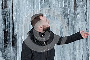 Man standing against cliff full of icicles