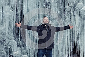 Man standing against cliff full of icicles