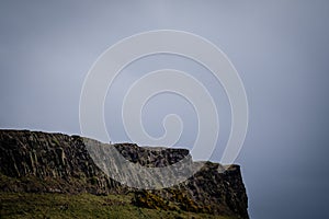 Man standing alone at Salisbury Crags in Edinburgh during a cloudy day, telephoto