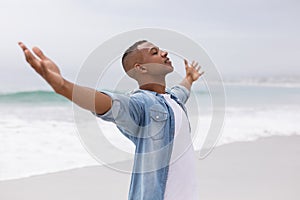 Man standing with arms outstretched on the beach