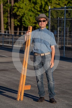 A man standing around, holding his wooden stilts.