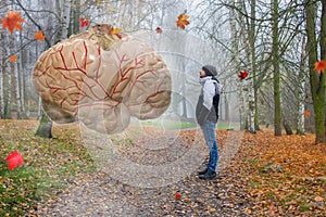A man standing in a autum landscape in front of giant human brain. The brain is currently transmitting information and operations