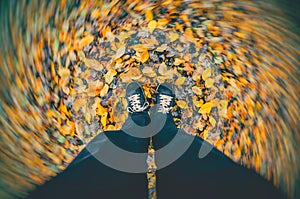 Man standing in the autumn park on dry fallen leaves. Strong wind blowing leaves around