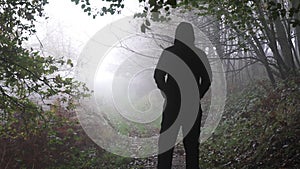 A Man, Standing Back To Camera. On A Moody stormy Autumn Day in a woodland