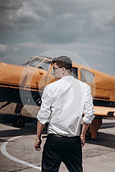 A man standing on the background of a small single engine plane.