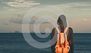 Man standing with backpack and green riding hood looking sea. concept for adventure and travel  in summer vacations and outdoor al