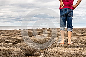 Man standing barefoot on the beach of stones on the seashore