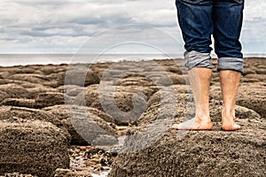 Man standing barefoot on the beach of stones on the seashore