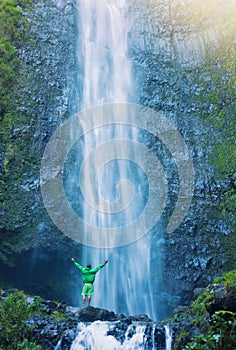 Man standing at base of massive waterfall