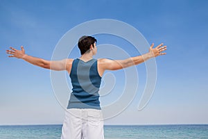 Man standing at beach with arms outstretched