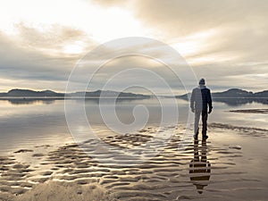 Man standing at the beach, reflections of the man in the water. Calm sea, mist and fog. Hamresanden, Kristiansand
