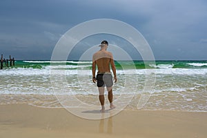 Man standing at the beach and watching the ocean