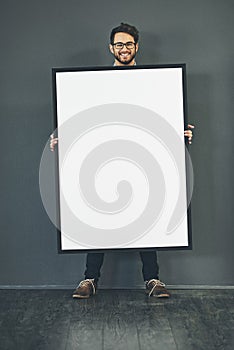 Man standing with a blank sign or portrait frame, showing copy space for advertising or marketing with dark background