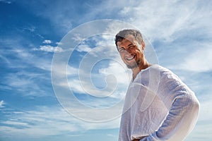 Man standing before blue skies with clouds