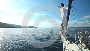 Man standing on the bow of sailing boat on Mediterranean sea.