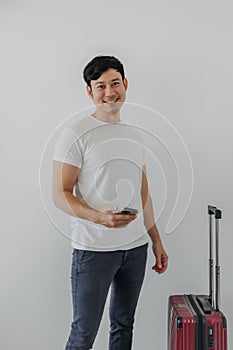 Man is standing with a briefcase, using mobile phone.