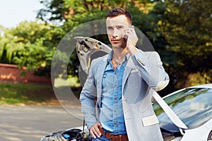 Man standing at a broken car and calling