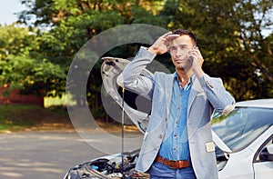 Man standing at a broken car and calling