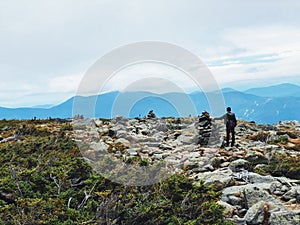 A man standing by cairn marker on Mt. Washington