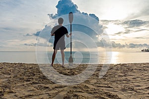 Man standing on clear sand beach and hold Paddle