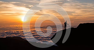 Man standing on cliff above the cloudy valley