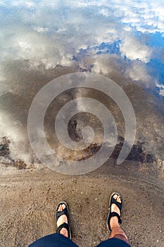 Man standing on coast near river water surface with reflections photo