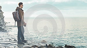 Man standing on coastline with photo camera