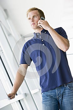 Man standing in corridor smiling using phone