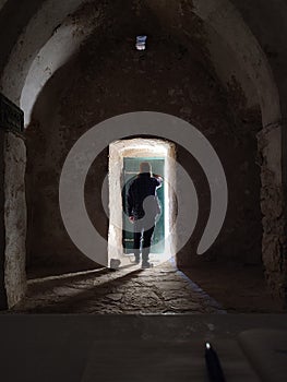 Man standing in dark space in front of door with shining light