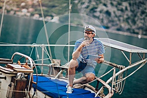 Man standing on the deck of his boat and using digital tablet on a sunny afternoon