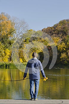 Man standing on the dock. Autumn, sunny. Back view