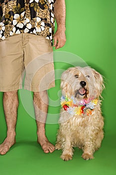 Man standing with dog wearing lei.