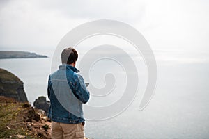 Man is standing on edge of the cliff on Irish sea