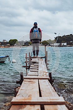 man standing at edge of the small fishing pier looking at stormy sea