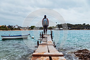 man standing at edge of the small fishing pier looking at stormy sea