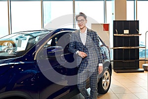 Man standing in front of a car in a showroom and posing to the camera