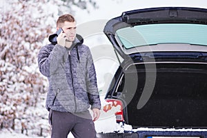 Man standing in front of damaged car and calling car services to