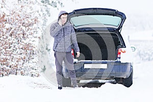 Man standing in front of damaged car and calling car services to