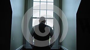 A man is standing in front of a window in a dark room