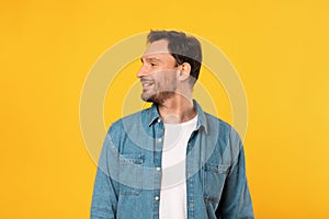 Man Standing in Front of Yellow Background, Looking Aside photo