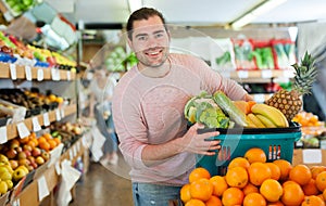 Man standing with full grocery cart during shopping in fruit shop