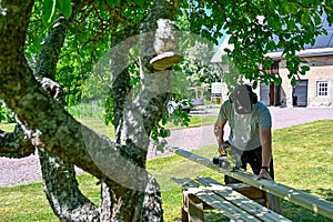 man standing in garden cutting planks with circle saw