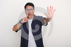 Man standing and gesturing a secret not to tell