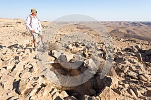 Man standing grave looking at desert crater moutains landscape.