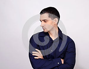 Man standing with his arms crossed looking down over the shoulder to the side from profile.