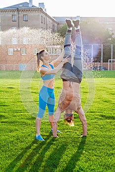 Man standing on his hands upside down and woman holding him. Strong, muscular extreme sportsmen. Young athletes of Caucasian