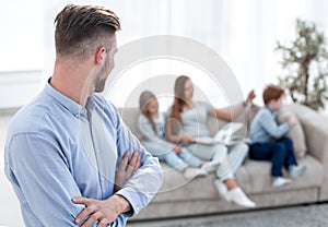 Man standing in his living room and looking at his family