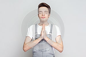 Man standing holding hands in namaste or prayer, keeping eyes closed while practicing yoga.