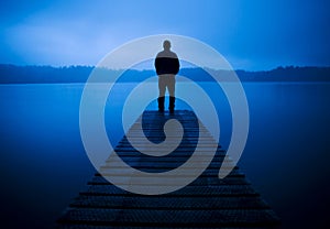 Man Standing on a Jetty by Tranquil Lake Concept