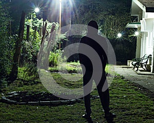 Man standing on a lawn looking at the stars in the night sky during a cold winter night. long exposure shot of a man wearing his w